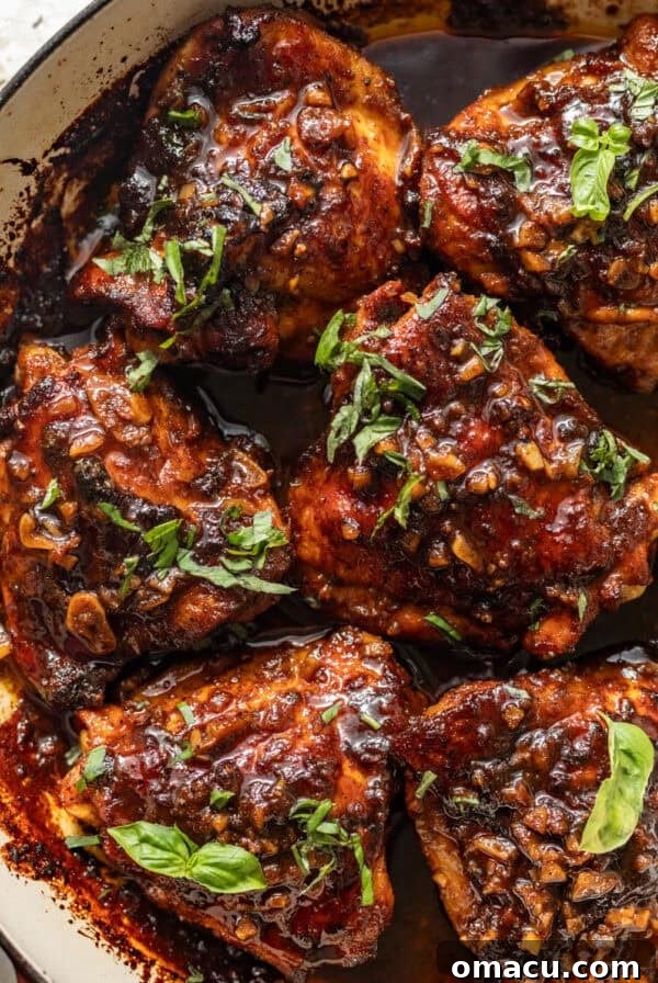 honey garlic chicken thighs in a skillet topped with a sticky honey garlic glaze and chopped parsley.