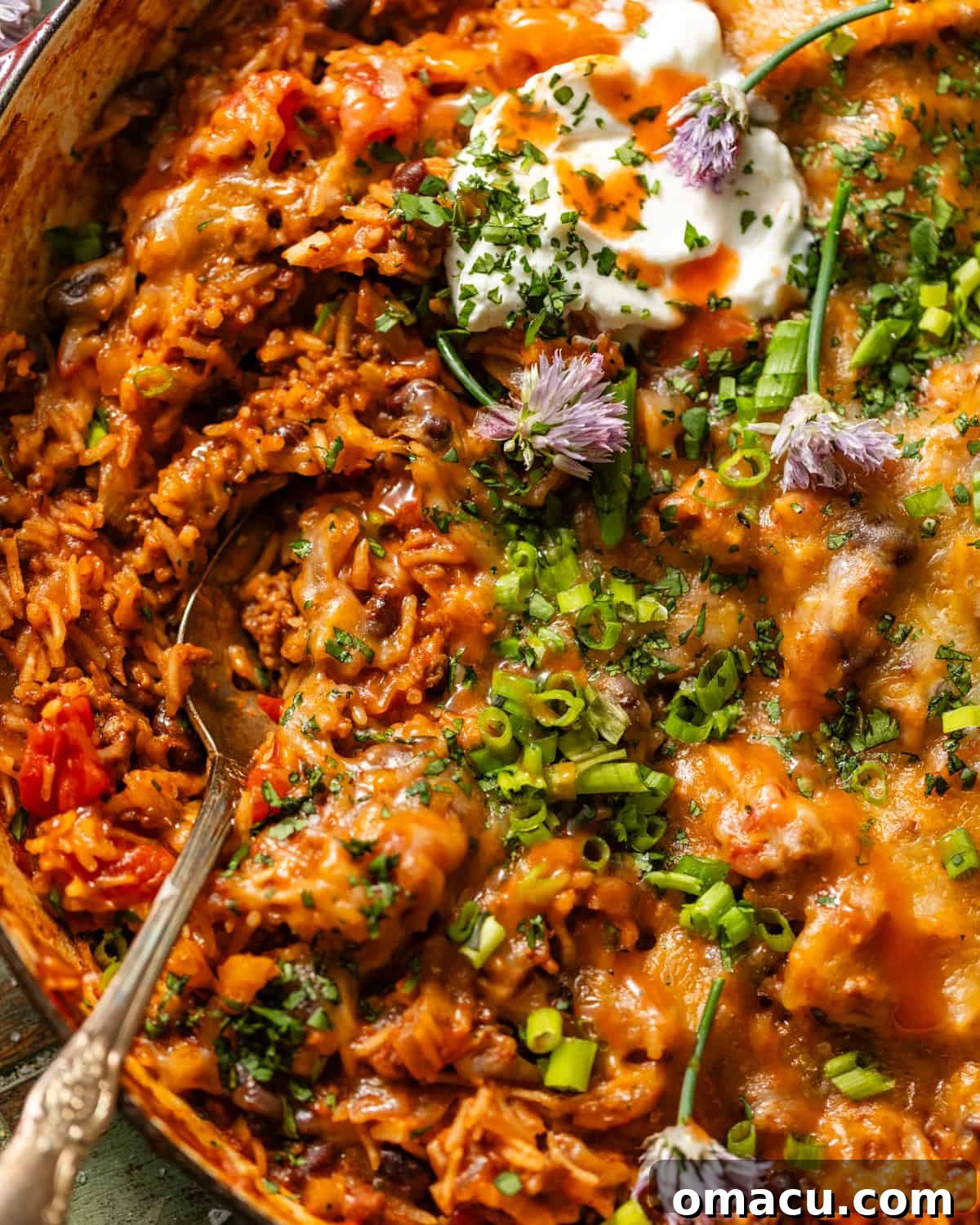 a spoon scooping the taco rice out of the skillet.
