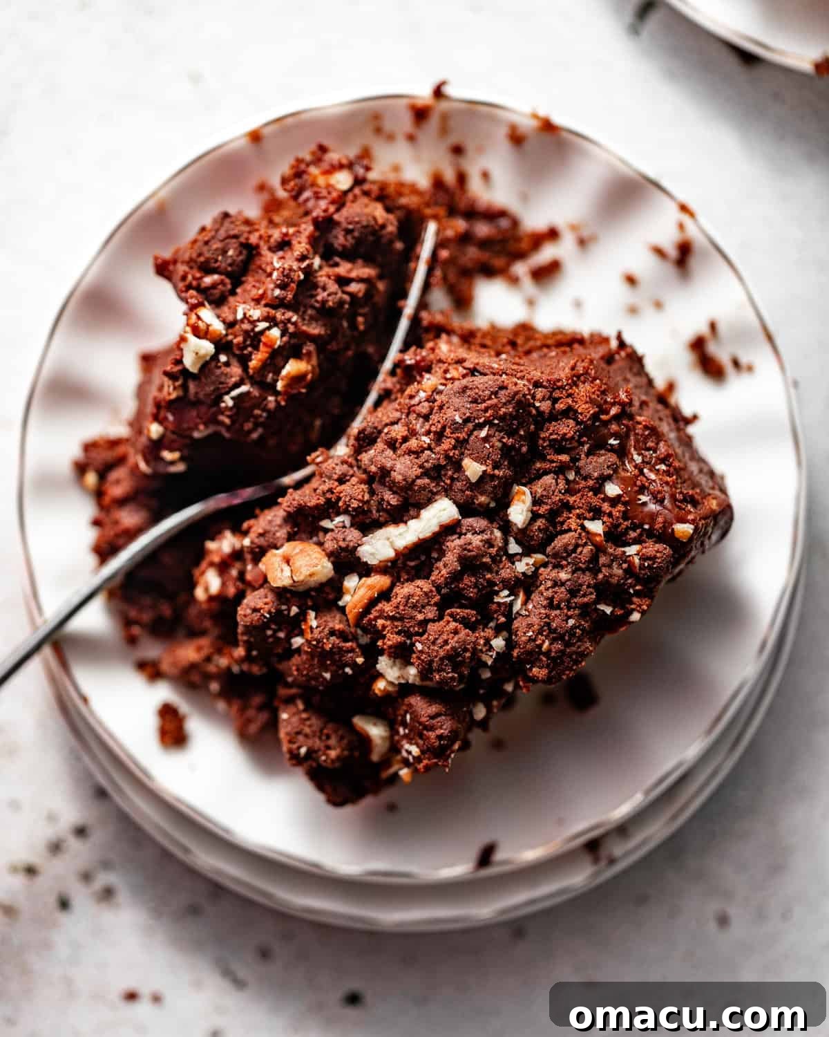 photo of texas sheet cake on a plate topped with chocolate fudge frosting and chocolate crunch topping.