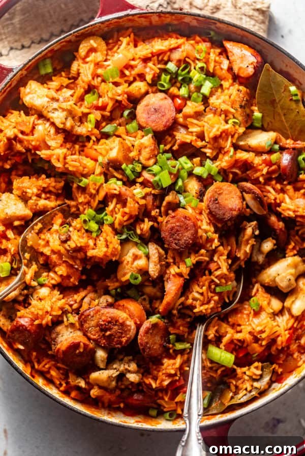 chicken and sausage jambalaya in a large pot topped with chopped green onions with a serving spoon.