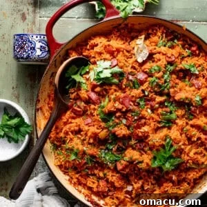 gullah red rice in a pot topped with fresh parsley with a wooden spoon scooping the rice.