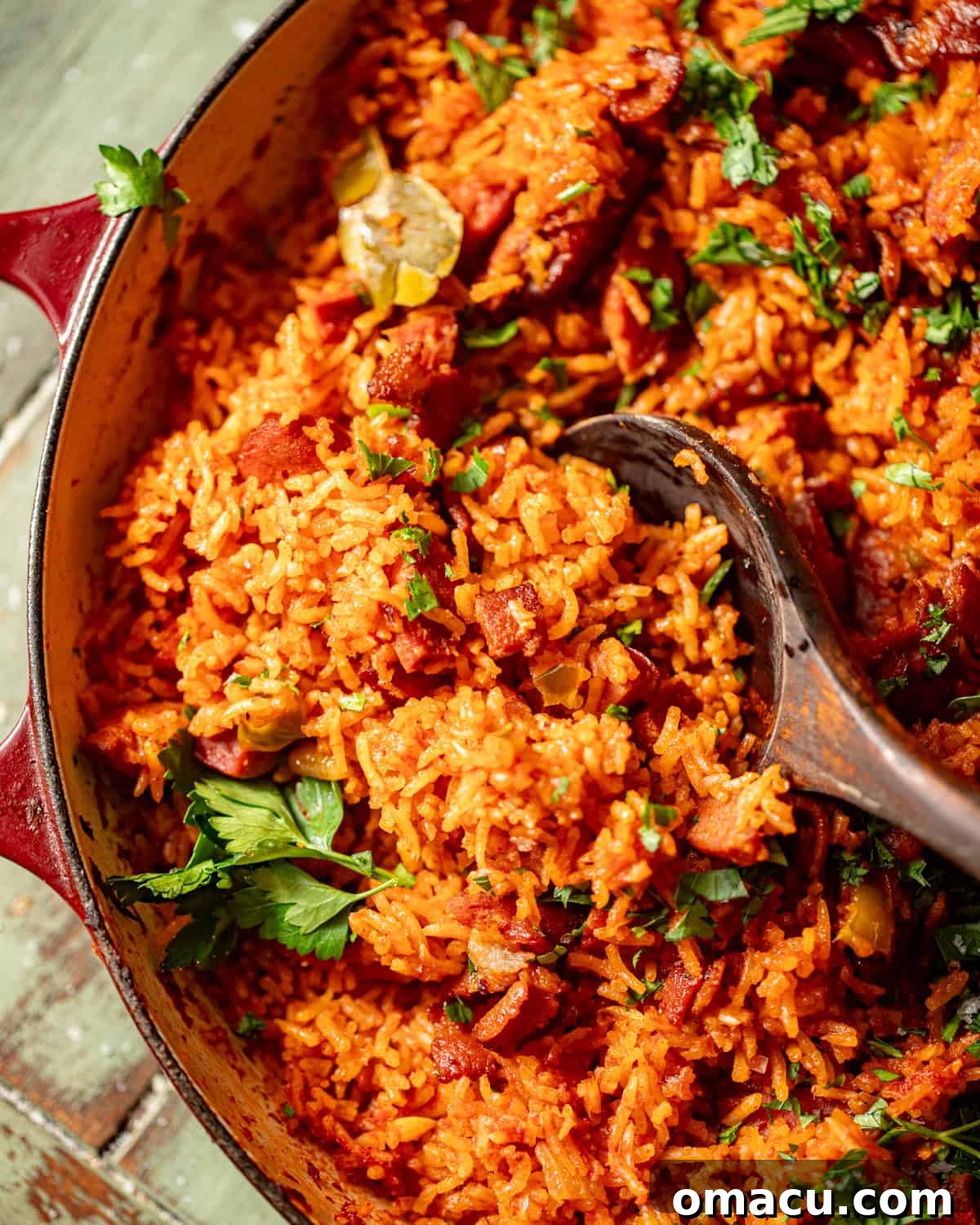 charleston red rice in a pan with a wooden spoon.