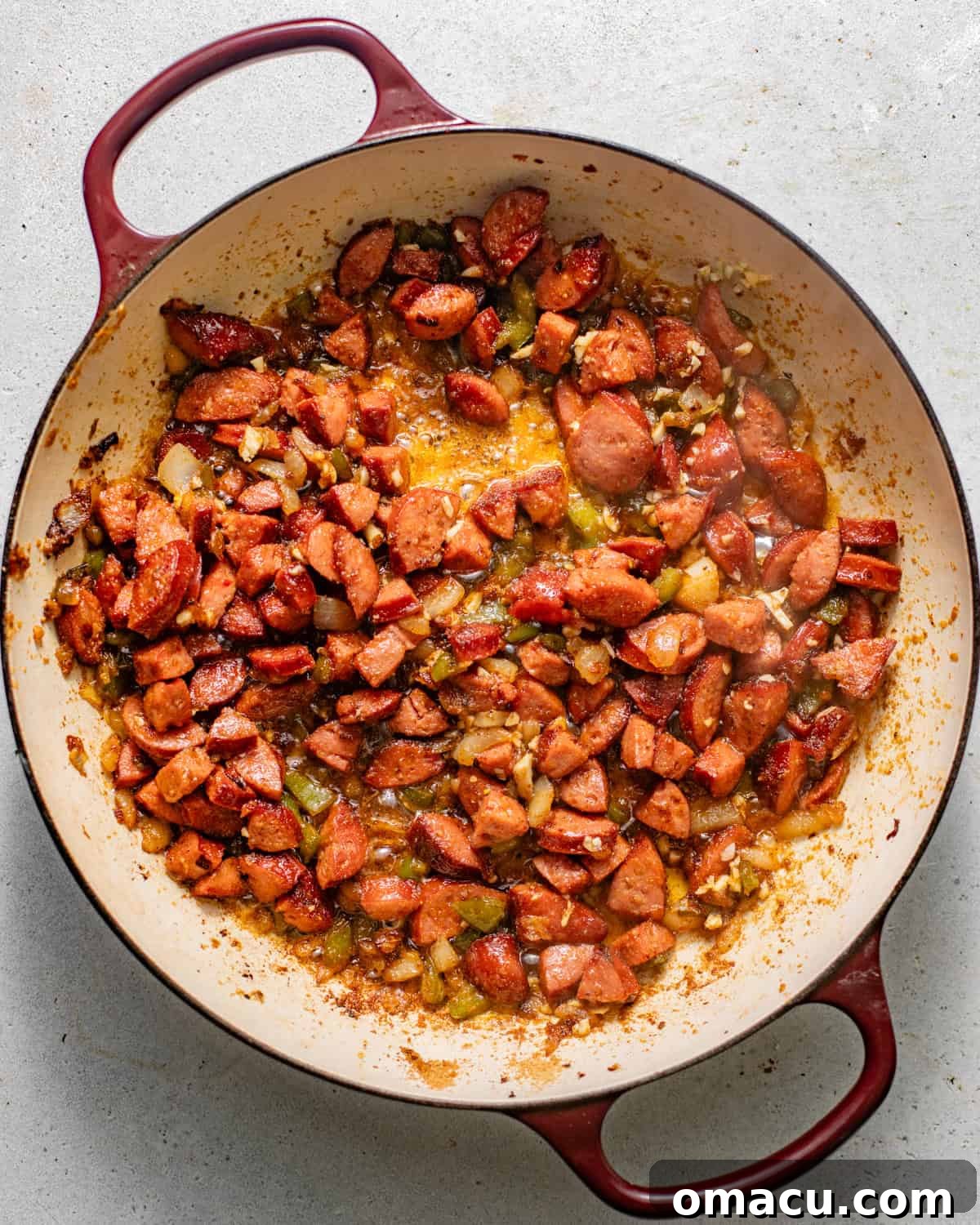 sausages, diced onion, and green bell pepper cooking in a large skillet until softened and slightly browned.
