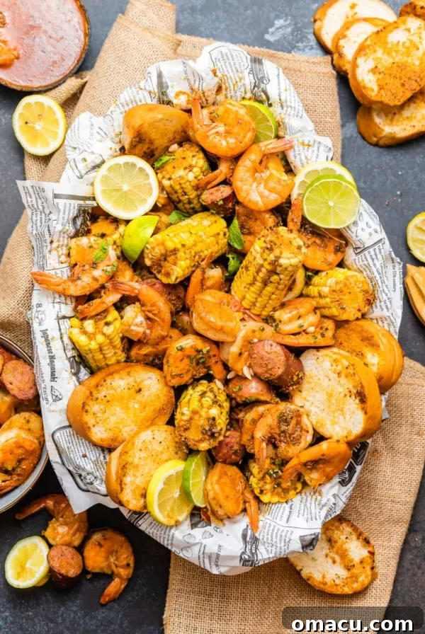 low country boil in a oval platter on top of newspaper surrounded by shrimp and sliced bread.