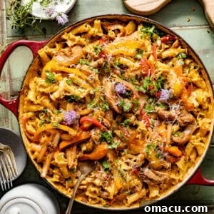 rasta pasta in a large skillet topped with cilantro, sauteed bell peppers, and jerk chicken.