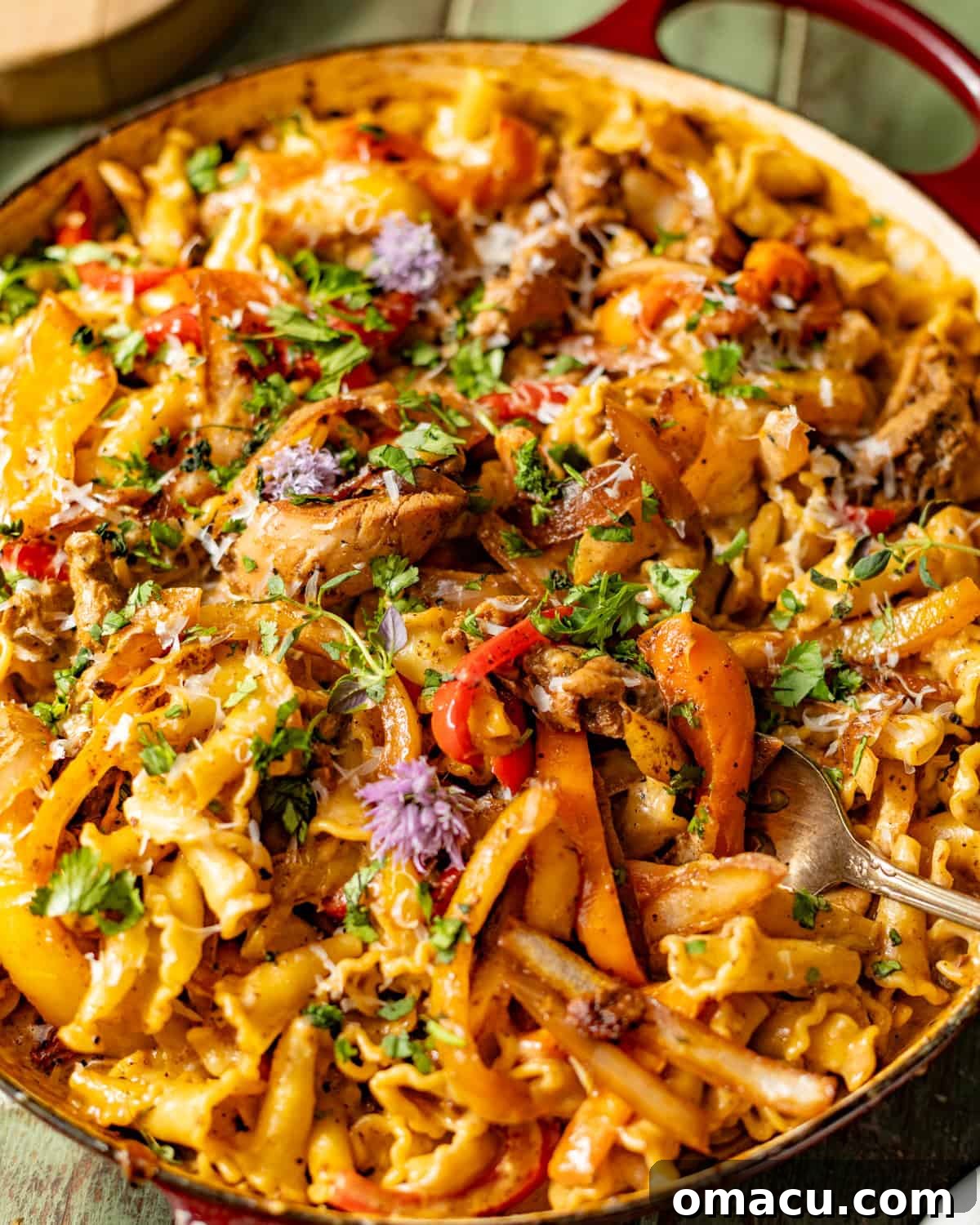 rasta pasta in a skillet with a spoon scooping out a portion to show the creamy sauce coated pasta.