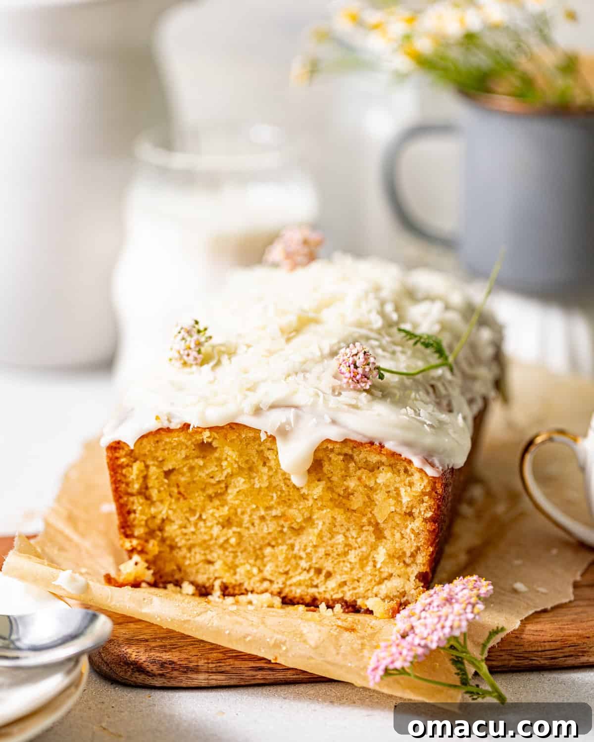 Moist Pineapple Quick Bread Recipe with Brown Sugar Glaze 2 pineapple bread on a cutting board topped with pineapple glaze and edible flowers.