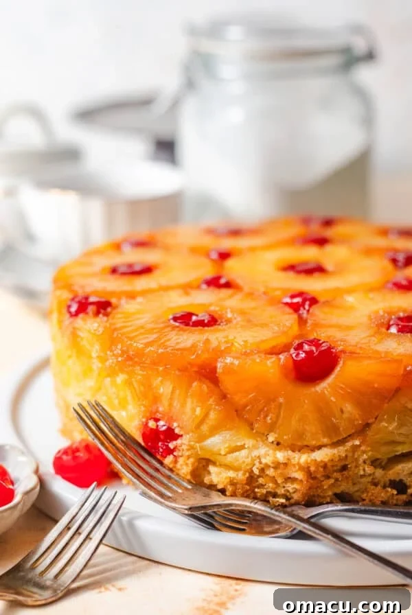 pineapple upside down cake recipe on a white surface with a bowl of cherries.
