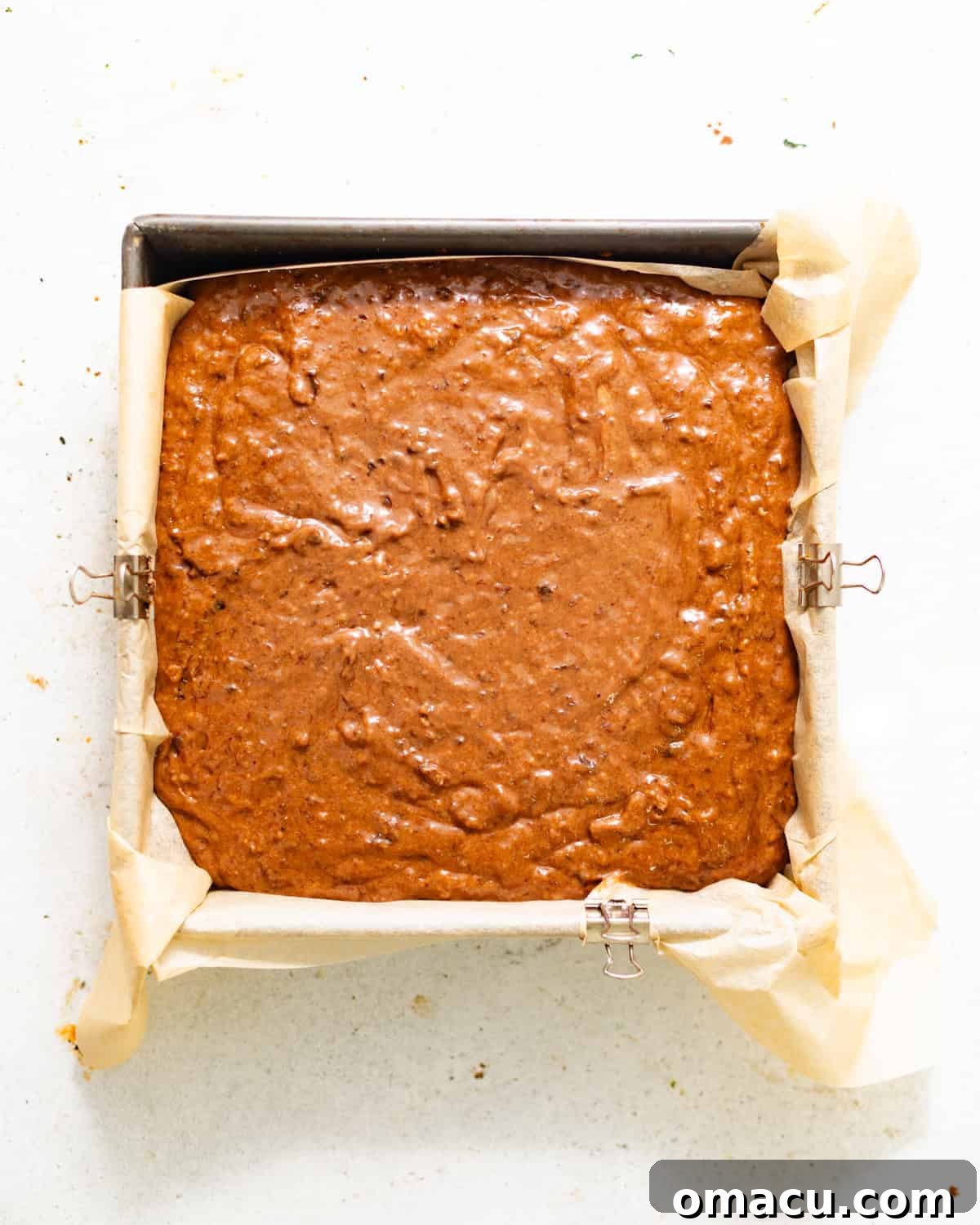 cake batter in a parchment paper lined square baking pan. 
