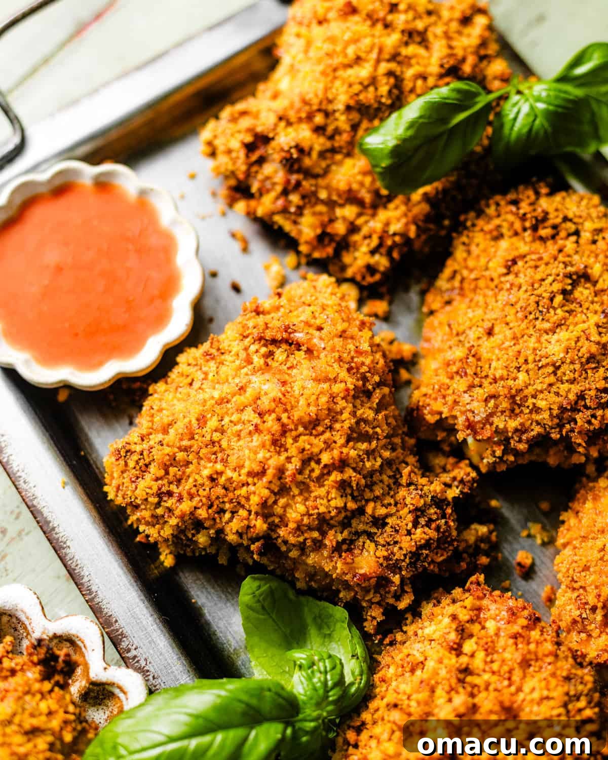 Crispy Oven-Baked Chicken That Tastes Like Fried Chicken 2 oven baked fried chicken on a serving tray next to a bowl of hot sauce.