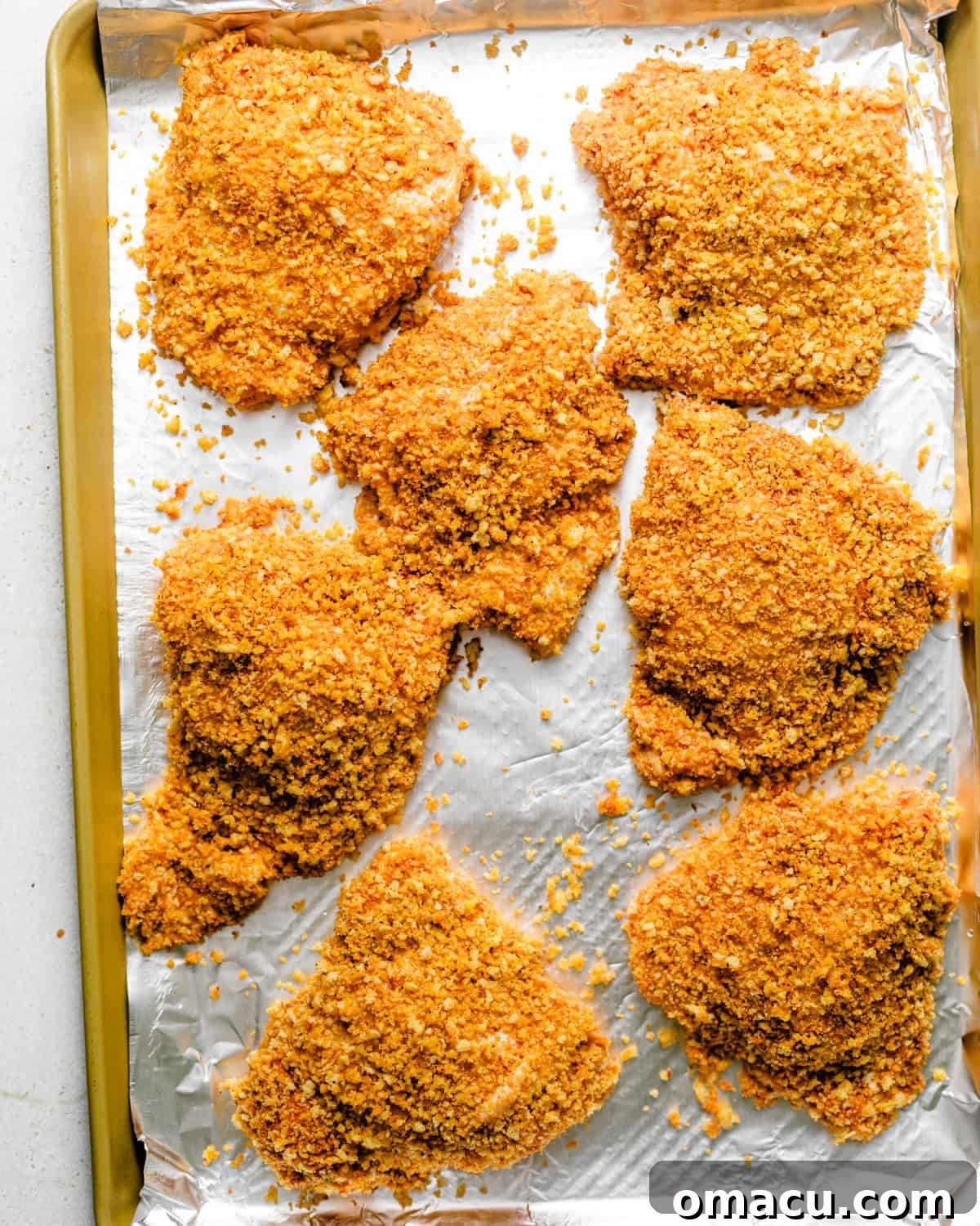 Crispy Oven-Baked Chicken That Tastes Like Fried Chicken 6 chicken coated in panko breadcrumbs and placed onto a wire rack on a foil lined rimmed baking sheet.