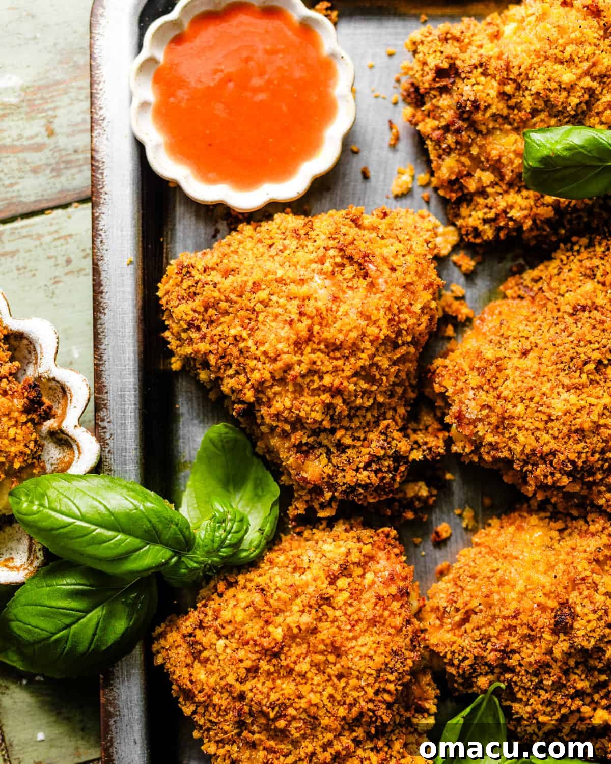 Crispy Oven-Baked Chicken That Tastes Like Fried Chicken 7 crispy oven fried chicken on a serving tray with a small bowl of hot sauce.
