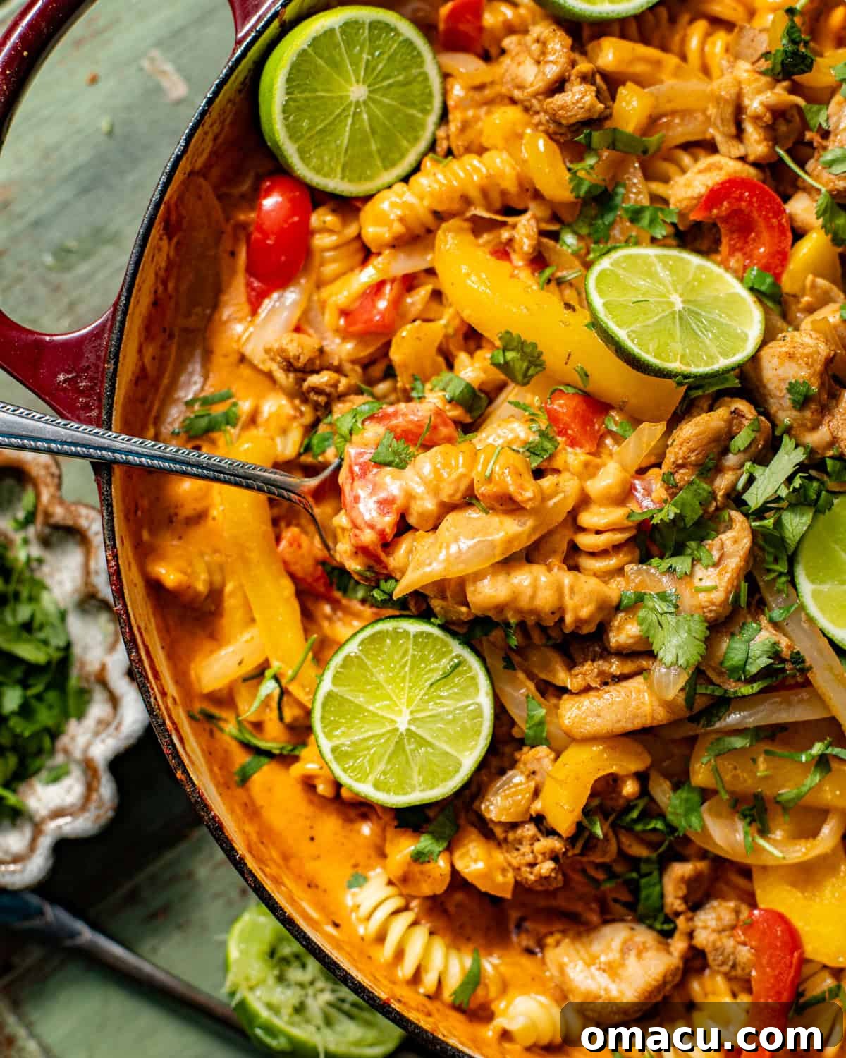 a spoon scooping out the chicken fajita pasta in the skillet.