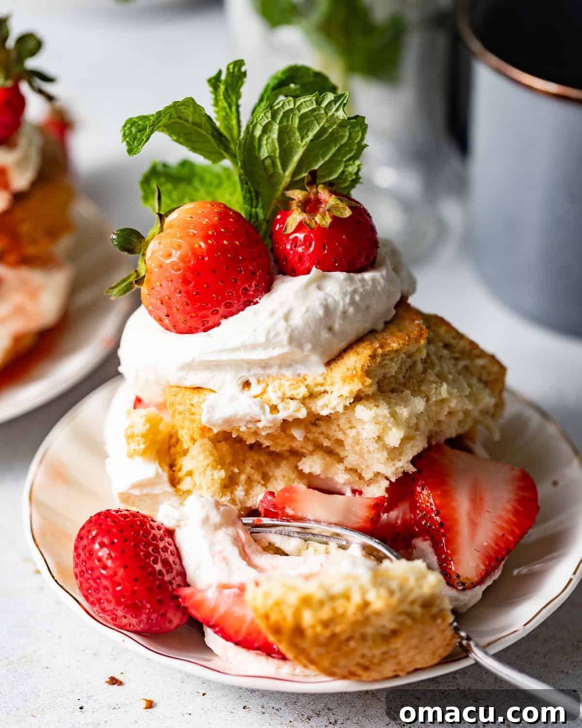 Strawberry Shortcake Recipe: Classic Layer Cake with Fresh Berries 3 a fork taking a scoop out of the strawberry shortcake so that you can see the tender texture of the biscuit.