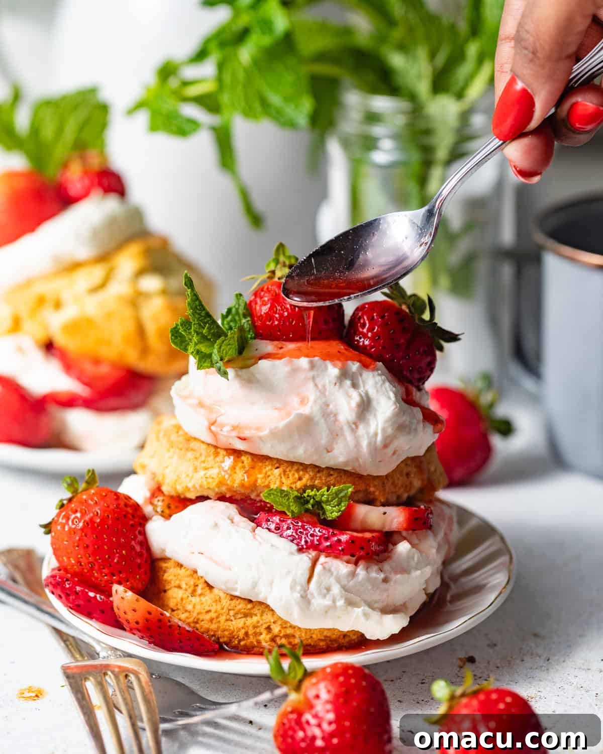 Strawberry Shortcake Recipe: Classic Layer Cake with Fresh Berries 10 strawberry shortcake on a small plate with strawberry syrup being poured on top.