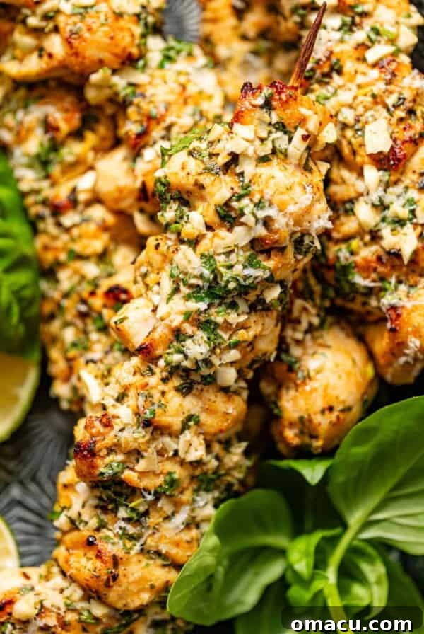 Garlic Butter Chicken Bites Recipe — Quick Savory Weeknight Meal 11 garlic parmesan chicken skewers on a serving plate with fresh basil and lemon slices.