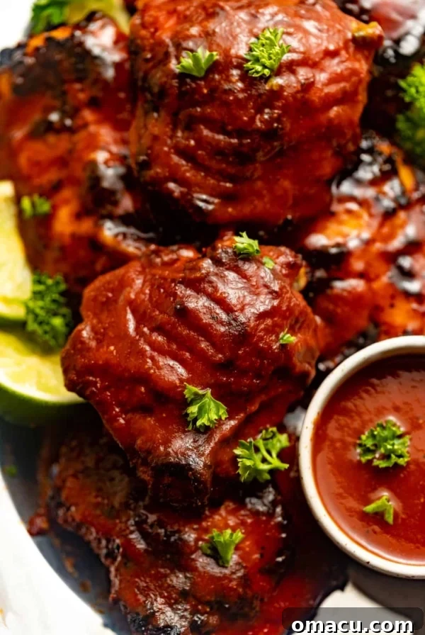 Garlic Butter Chicken Bites Recipe — Quick Savory Weeknight Meal 8 baked chicken thighs covered in bbq sauce on a silver plate.