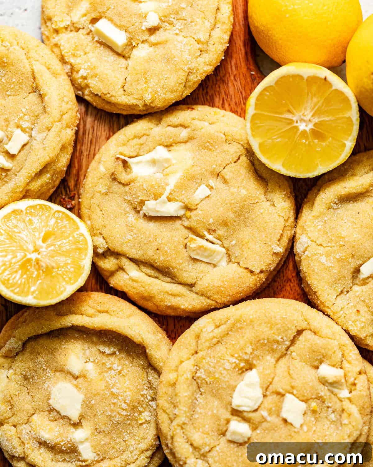 Zesty Lemon White Chocolate Chip Cookie Recipe 2 lemon white chocolate cookies on a board with sliced lemons.