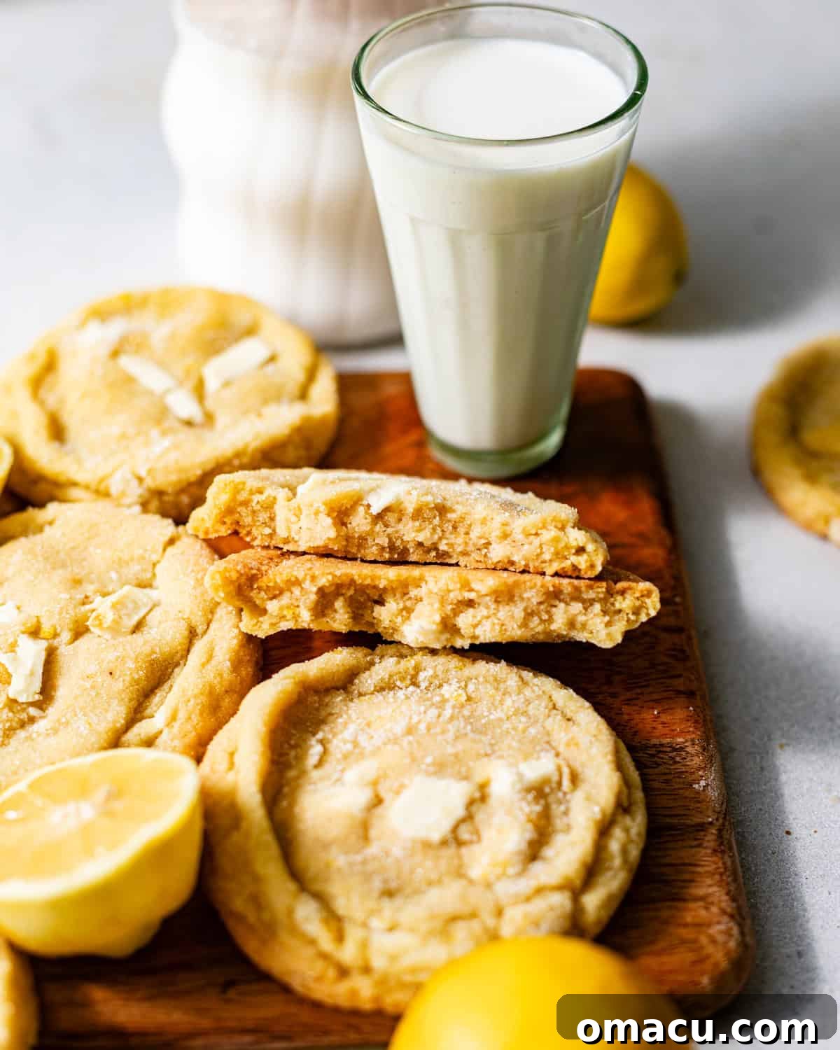 Zesty Lemon White Chocolate Chip Cookie Recipe 3 lemon white chocolate cookies on a board with a glass of milk.