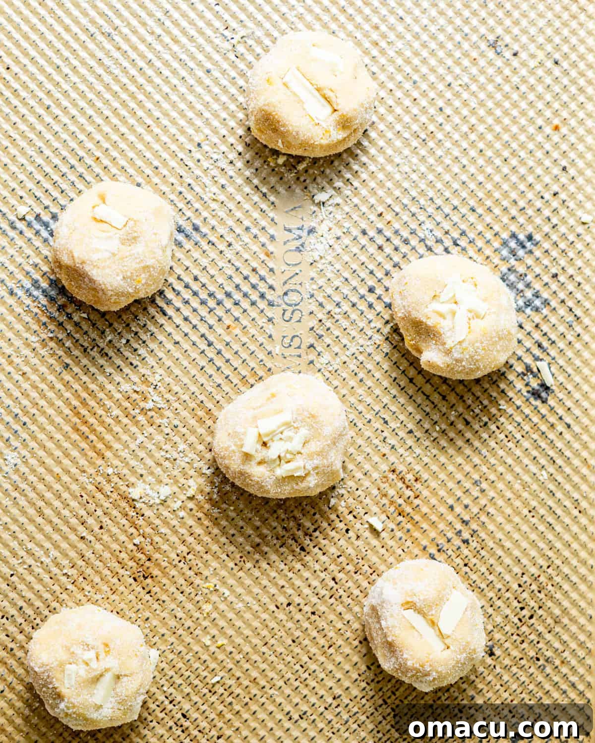 Zesty Lemon White Chocolate Chip Cookie Recipe 7 cookies on a baking sheet spaced out before baking.