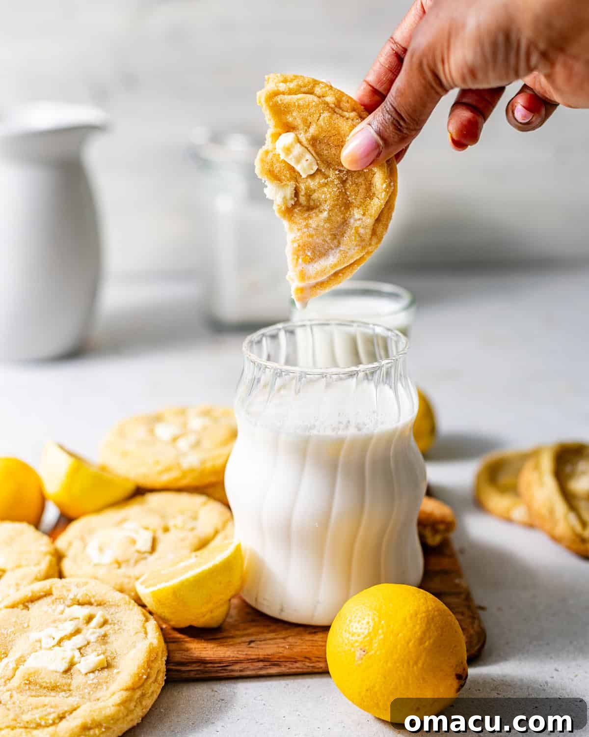 Zesty Lemon White Chocolate Chip Cookie Recipe 8 a hand dunking a cookie into a glass of milk.