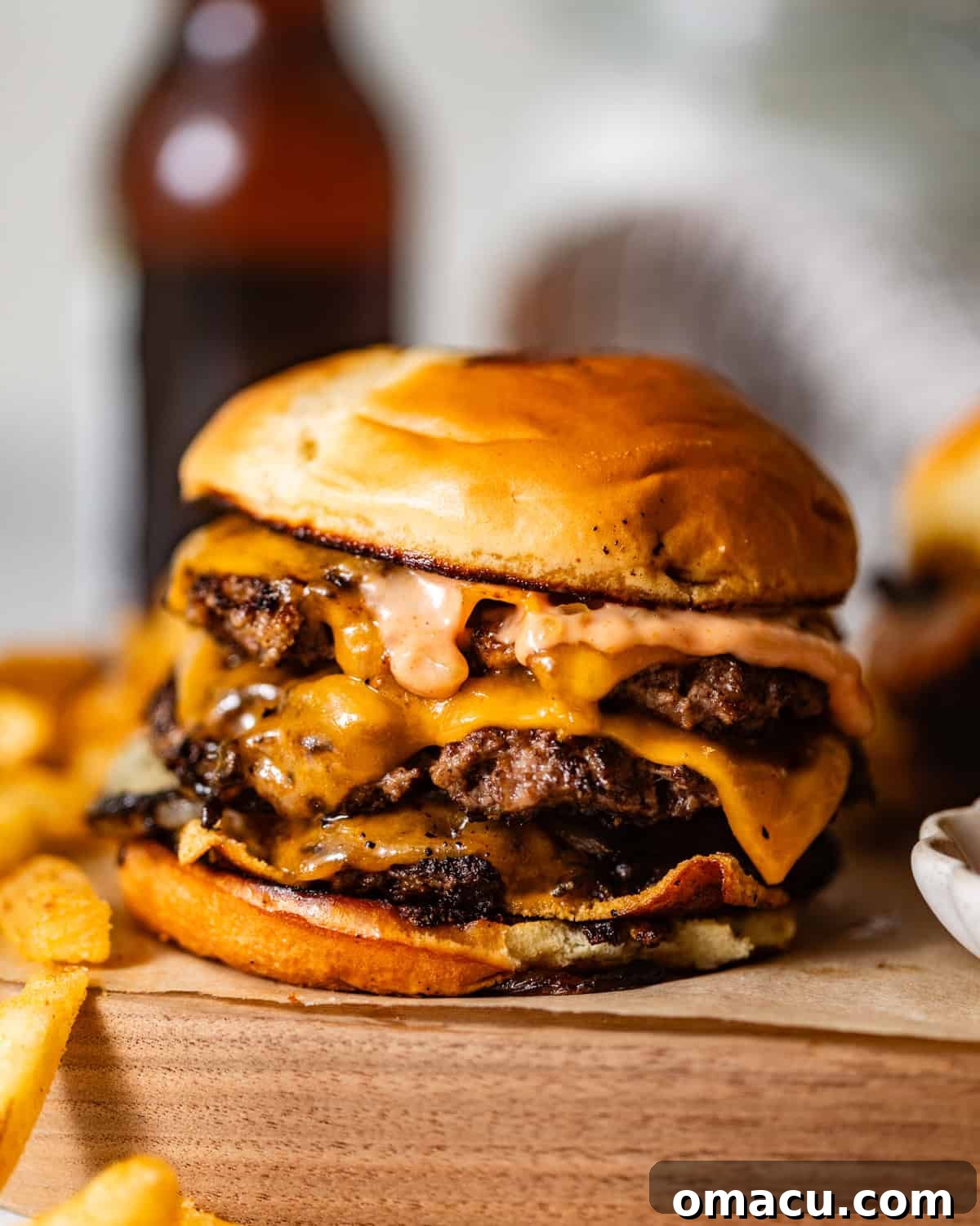 smash burger on a wooden board topped with fried onions, melted cheese, and burger sauce.