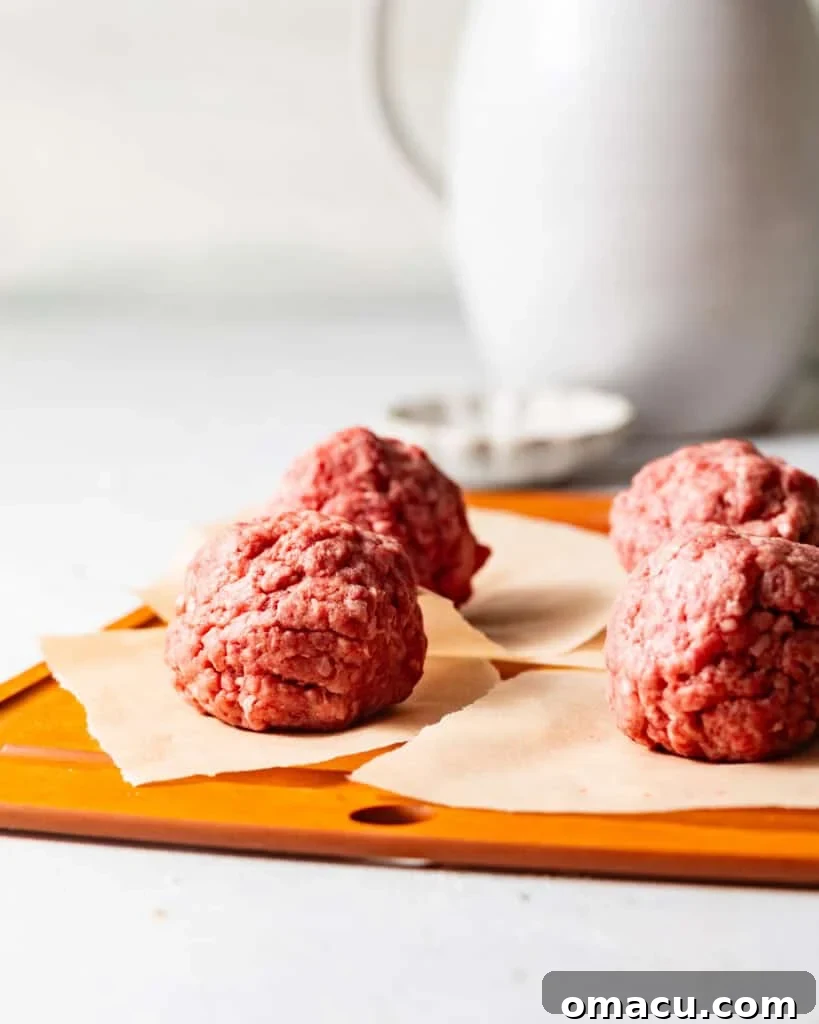 ground beef rolled into balls and placed onto parchment paper.