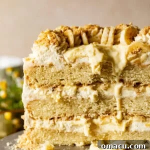 banana pudding cake on a cake stand with the cake cut open to see the inside layers.