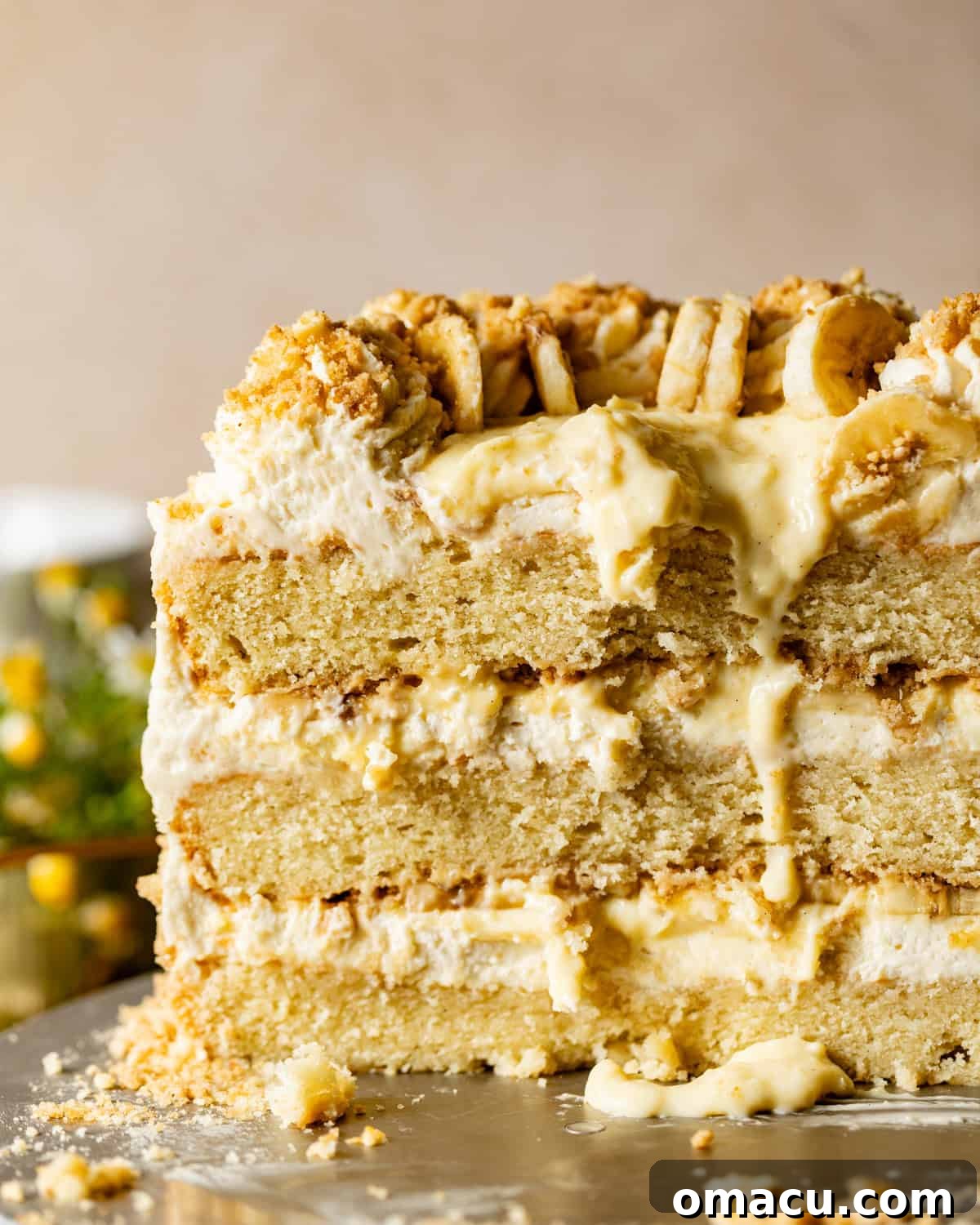 banana pudding cake on a cake stand with the cake cut open to see the inside layers.