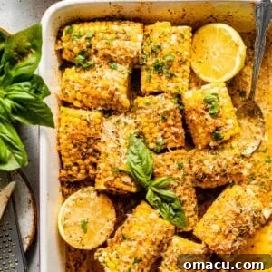 Oven-Baked Corn on the Cob with Garlic Herb Butter 11 baked corn on the cob in a baking dish covered in garlic butter and fresh herbs.