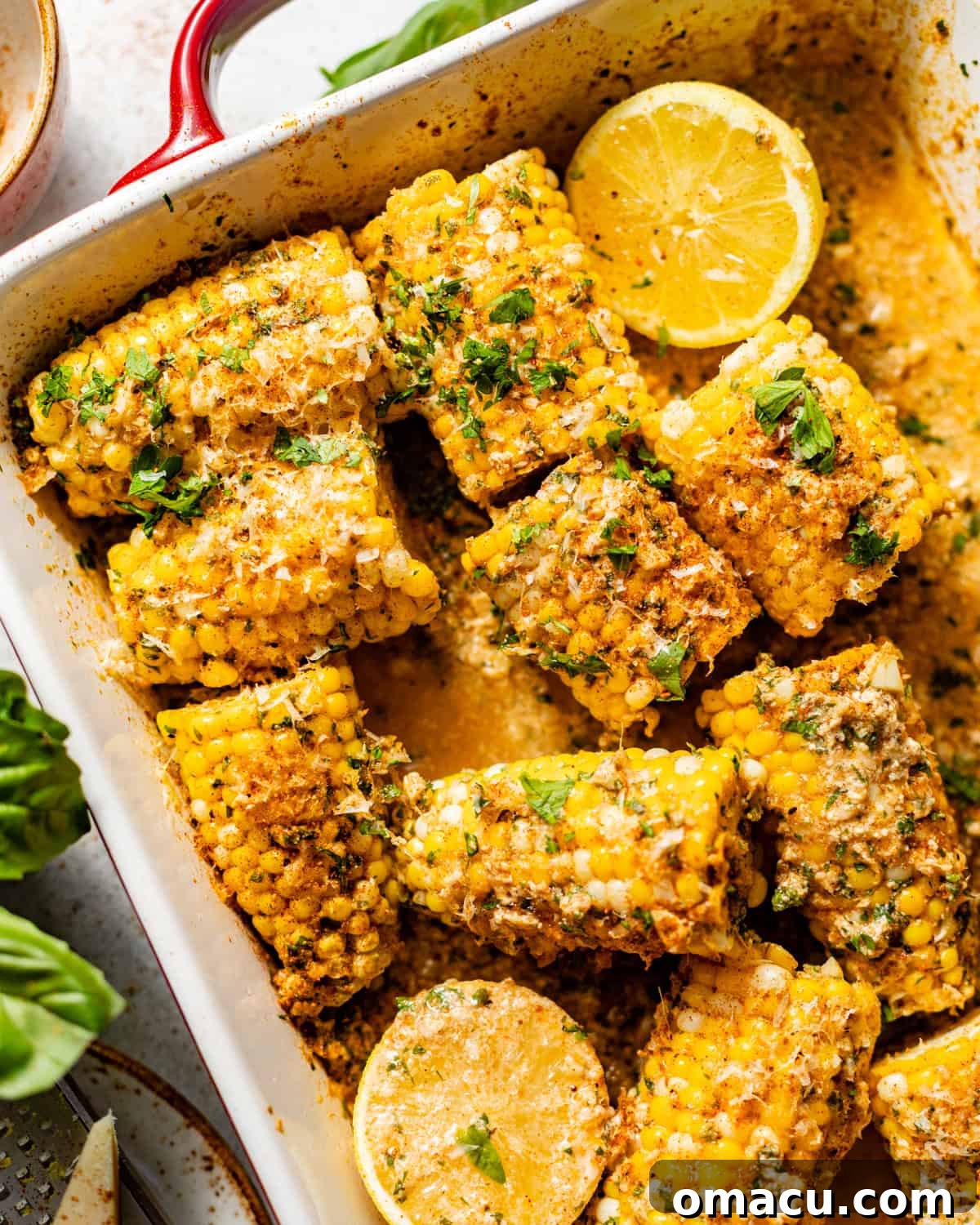 Oven-Baked Corn on the Cob with Garlic Herb Butter 6 corn in a baking dish covered in garlic butter.