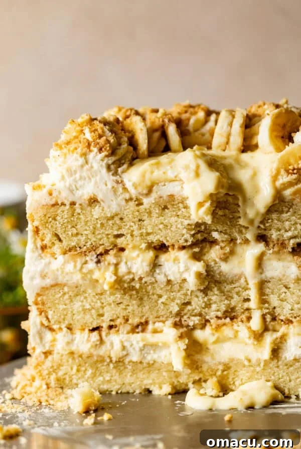 banana pudding cake on a cake stand with the cake cut open to see the inside layers.