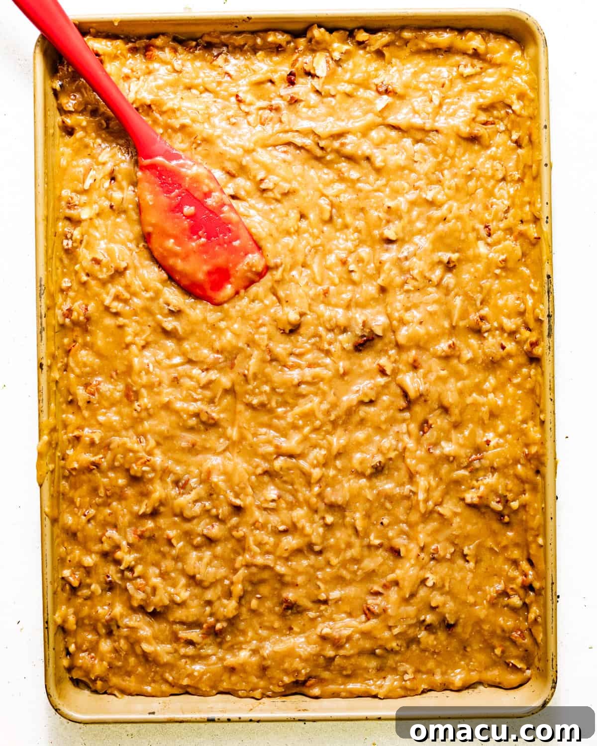 coconut pecan frosting spread out onto a baking sheet to cool and set.