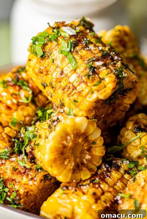 cajun corn on the cob stacked on top of each other covered in garlic butter.
