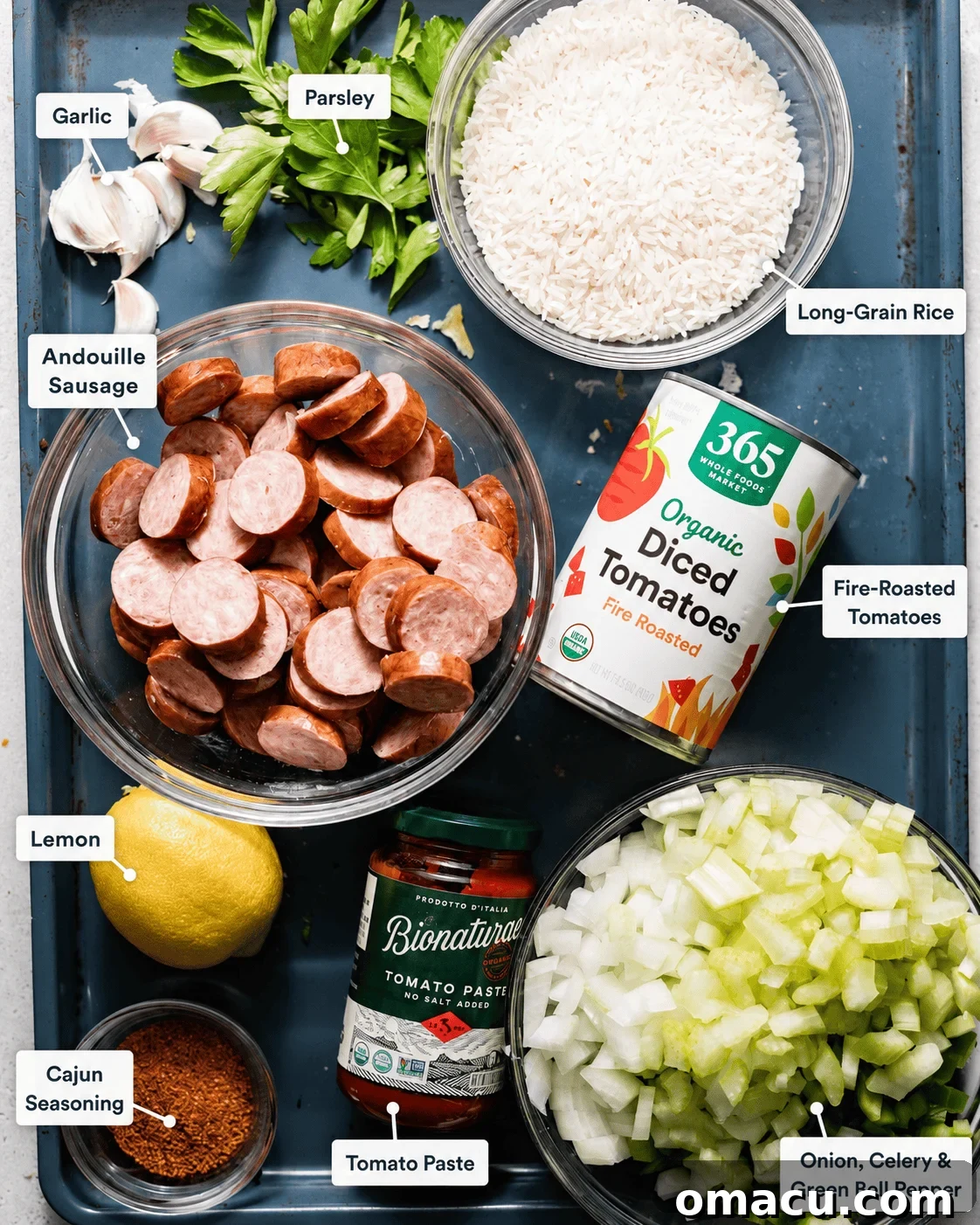 ingredients to make cajun sausage and rice skillet - andouille, onion, celery, green bell pepper, long grain rice, diced tomatoes, lemon juice, seasonings, garlic, tomato paste, and chicken broth.