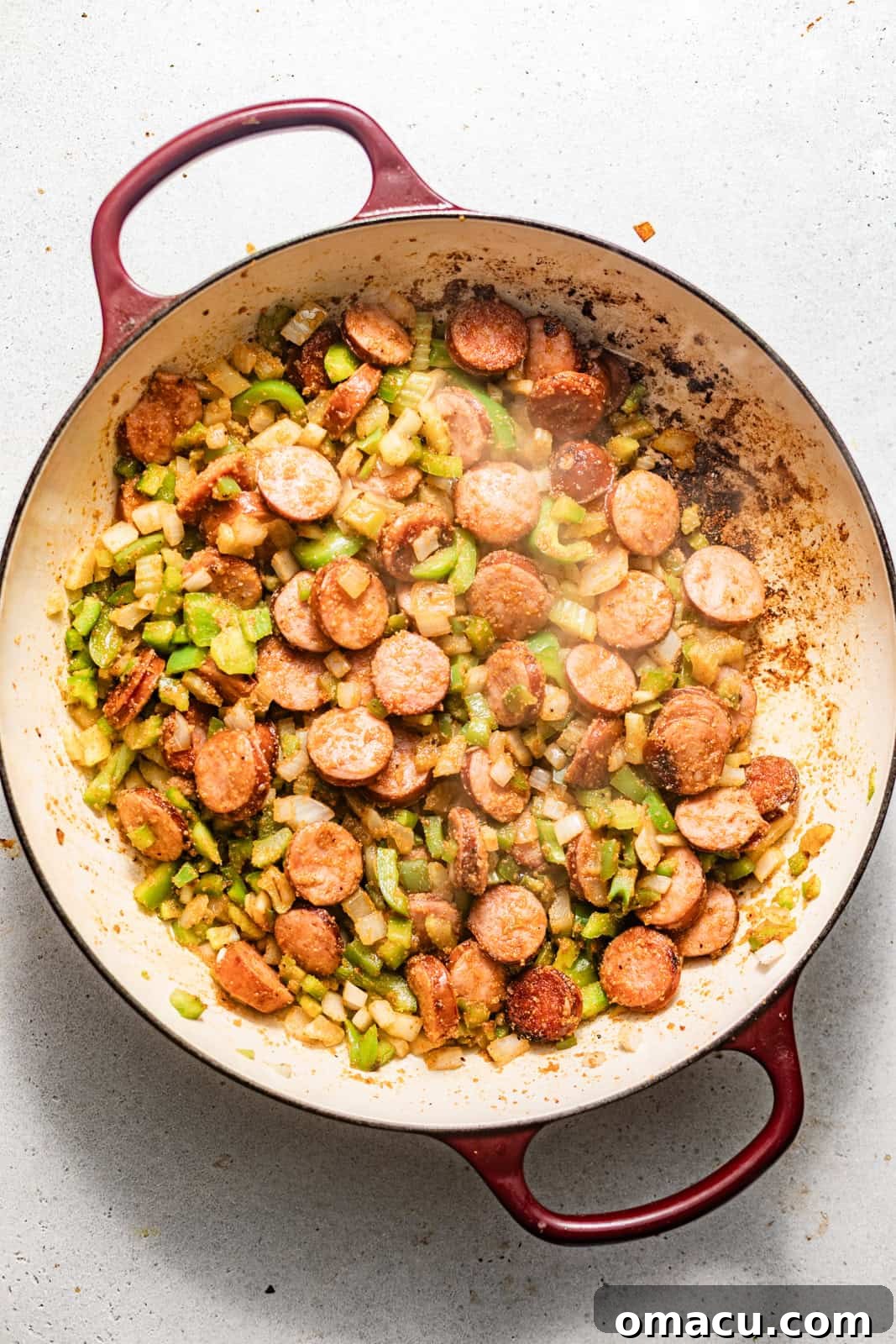 seared sausages and vegetables in a skillet.