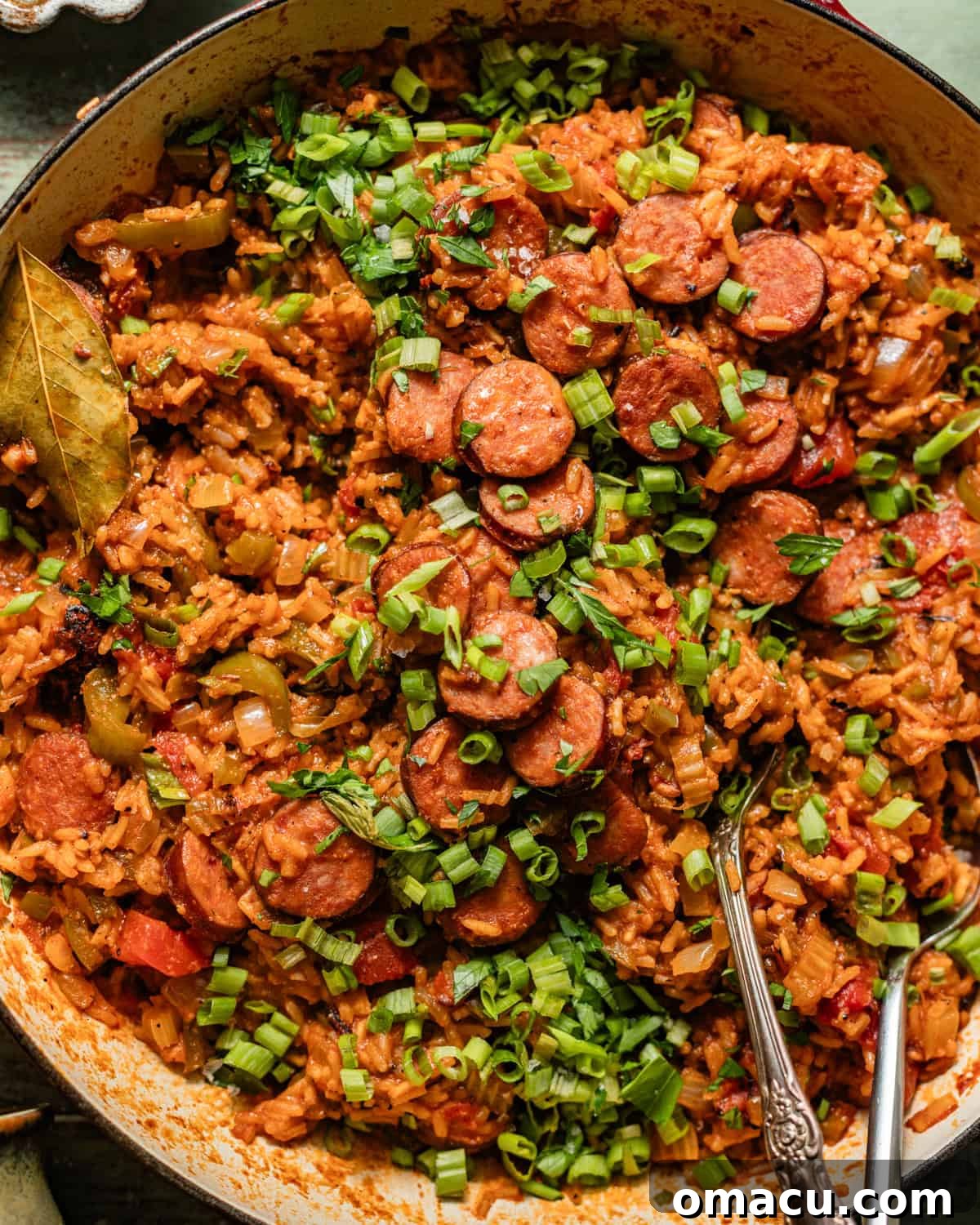 cajun sausage and rice in a skillet topped with chopped green onions.