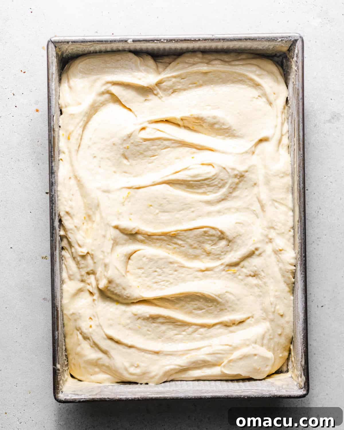 Moist Lemon Sheet Cake Recipe with Zesty Glaze 6 lemon cake batter added to a 9 by 13 baking dish.