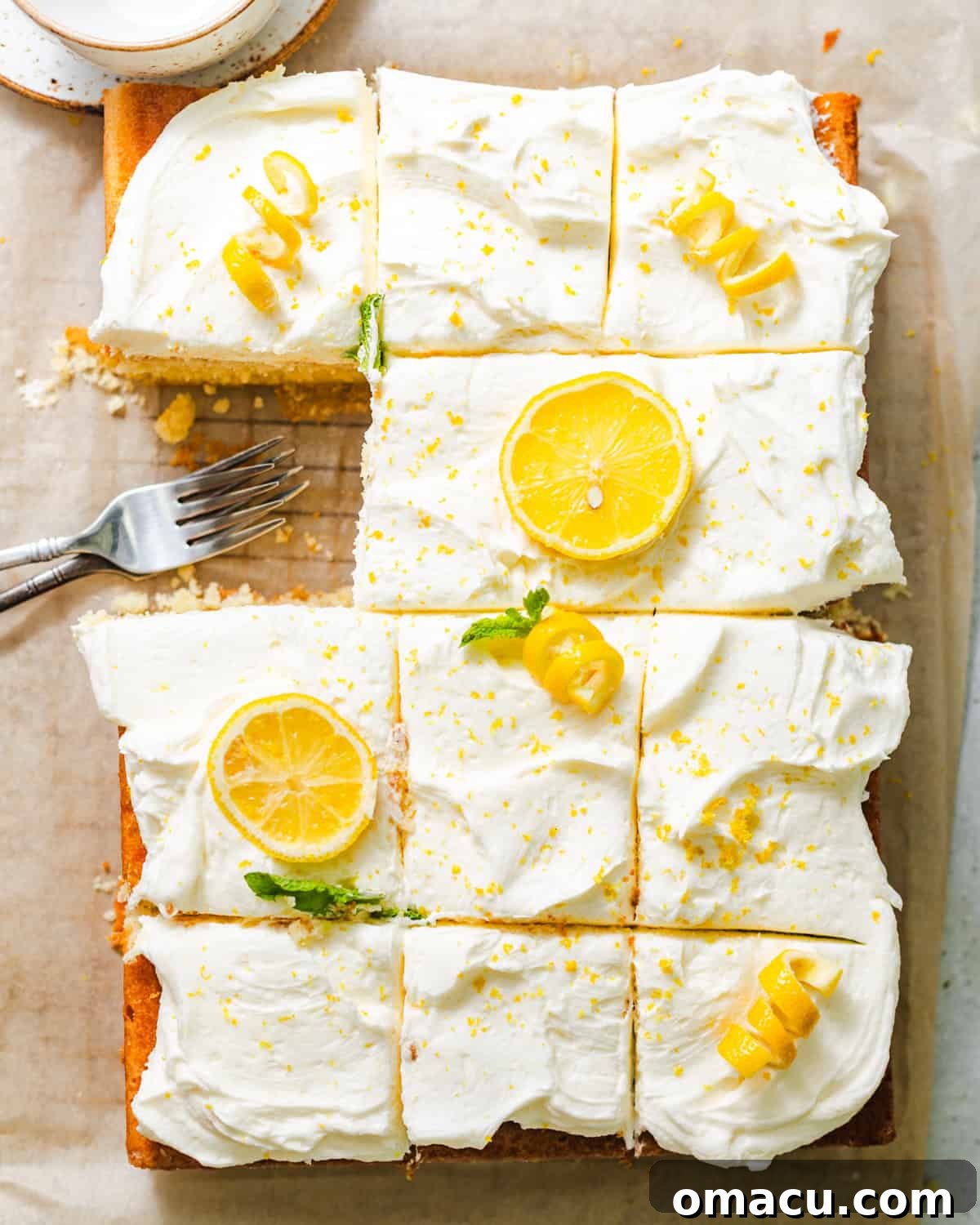 Moist Lemon Sheet Cake Recipe with Zesty Glaze 8 lemon sheet cake on a wire rack with lemon cream cheese frosting and fresh lemon zest and slices on top.