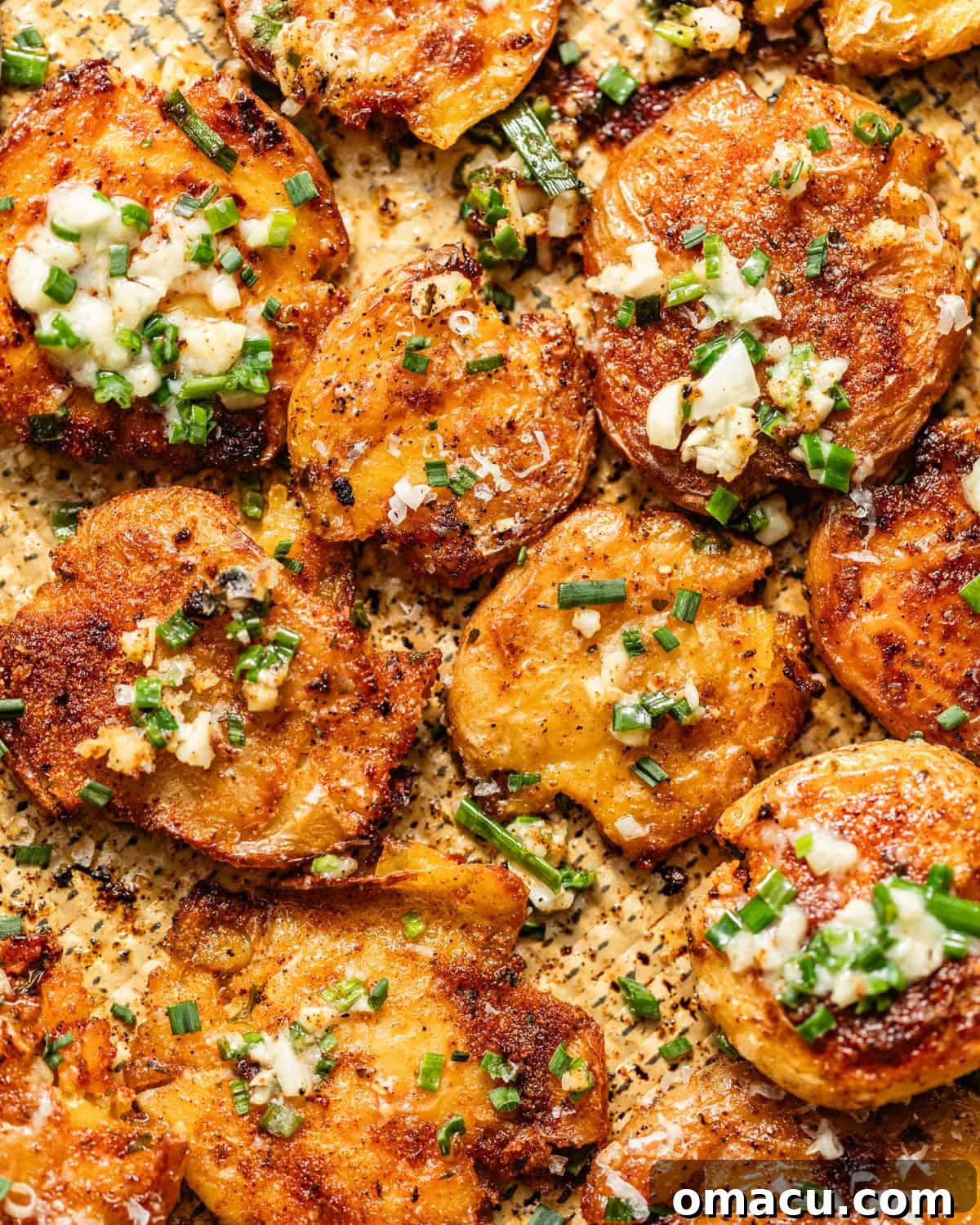 Crispy Garlic Parmesan Smashed Potatoes 2 garlic parmesan smashed potatoes on a baking sheet topped with garlic butter.
