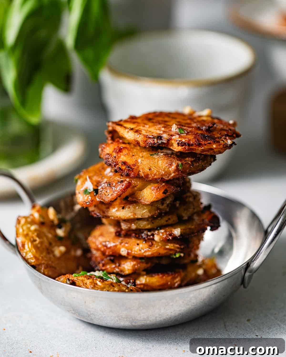 Crispy Garlic Parmesan Smashed Potatoes 8 parmesan smashed potatoes in a serving bowl stacked on top of one another.