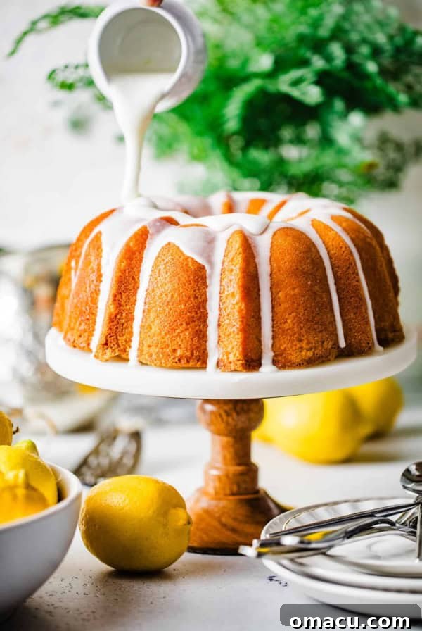 Sticky Cinnamon Roll Bundt Cake with Brown Sugar Glaze 10 lemon glaze being poured onto a lemon bundt cake on a cake stand.