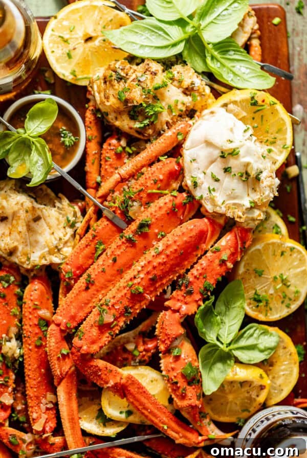 crab legs with garlic butter sauce on a serving board with lemon, basil, and a bowl of sauce.