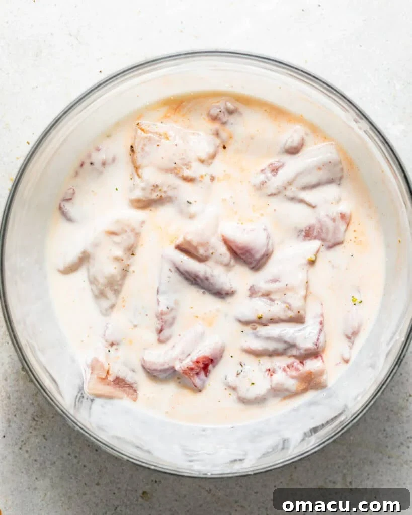catfish nuggets marinating in buttermilk and hot sauce.