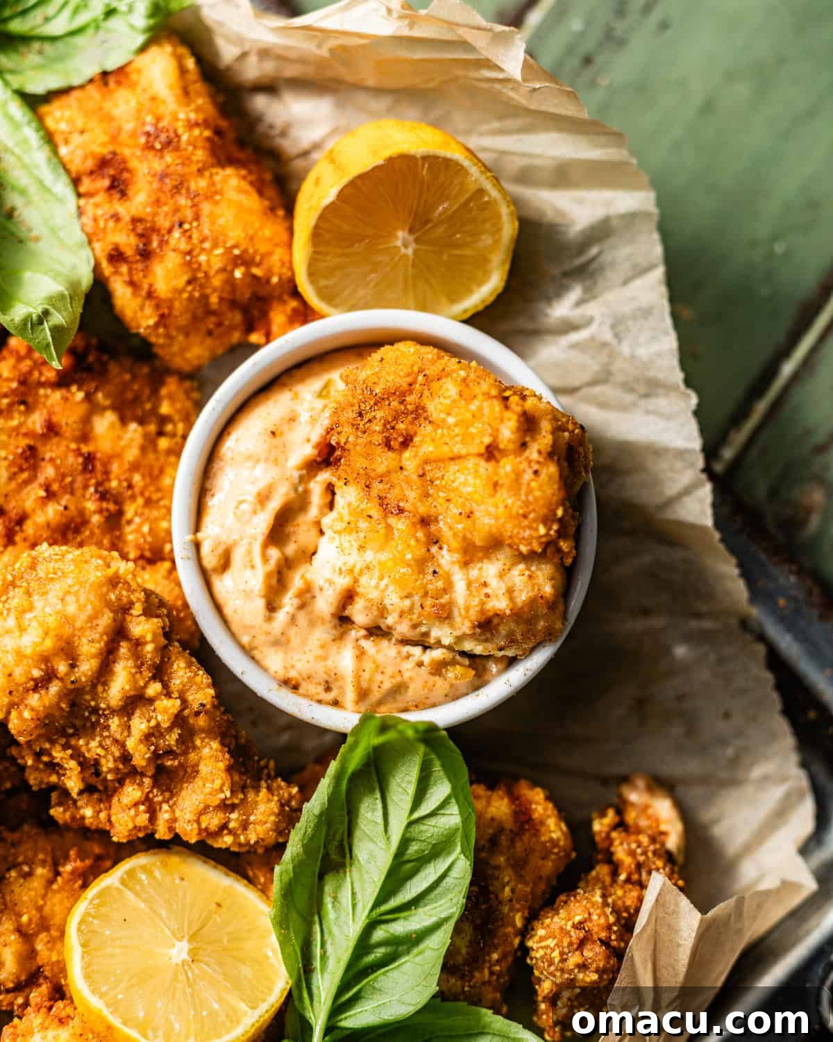 a catfish nuggets being dipped into a bowl of Cajun tartar sauce.