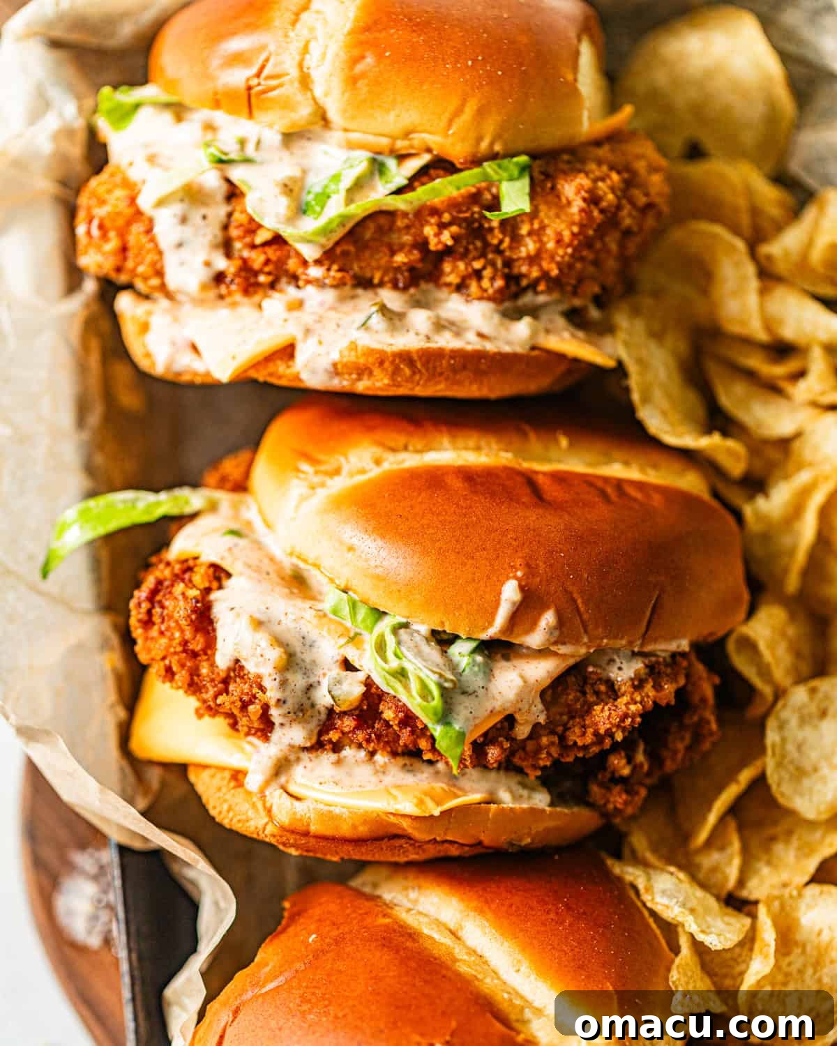 fried fish sandwiches in a serving tray with a side of potato chips.