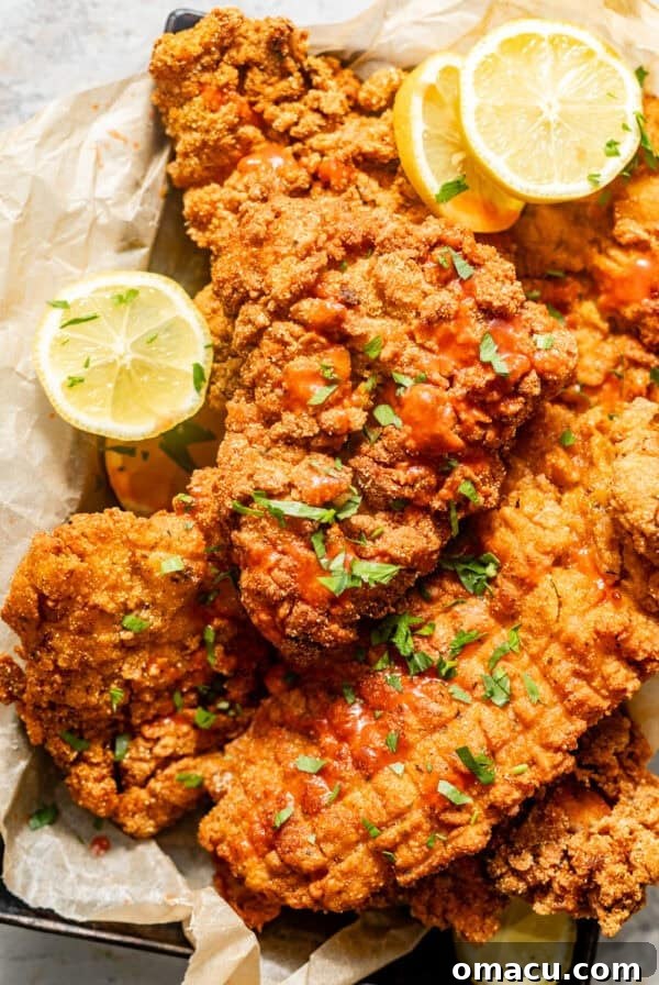 fried catfish in a basket lined with parchment paper and sliced lemons.