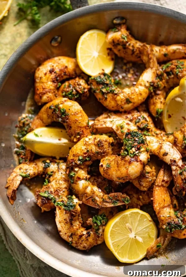 pan seared shrimp in a skillet with lemons and parsley.