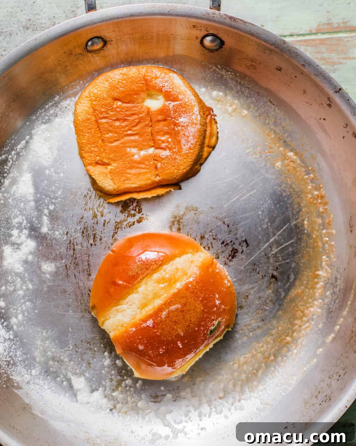 brioche buns in a pan being toasted in melted butter.