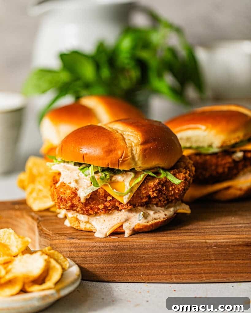 fried fish sandwiches on a serving board with a bowl of potato chips on the side.